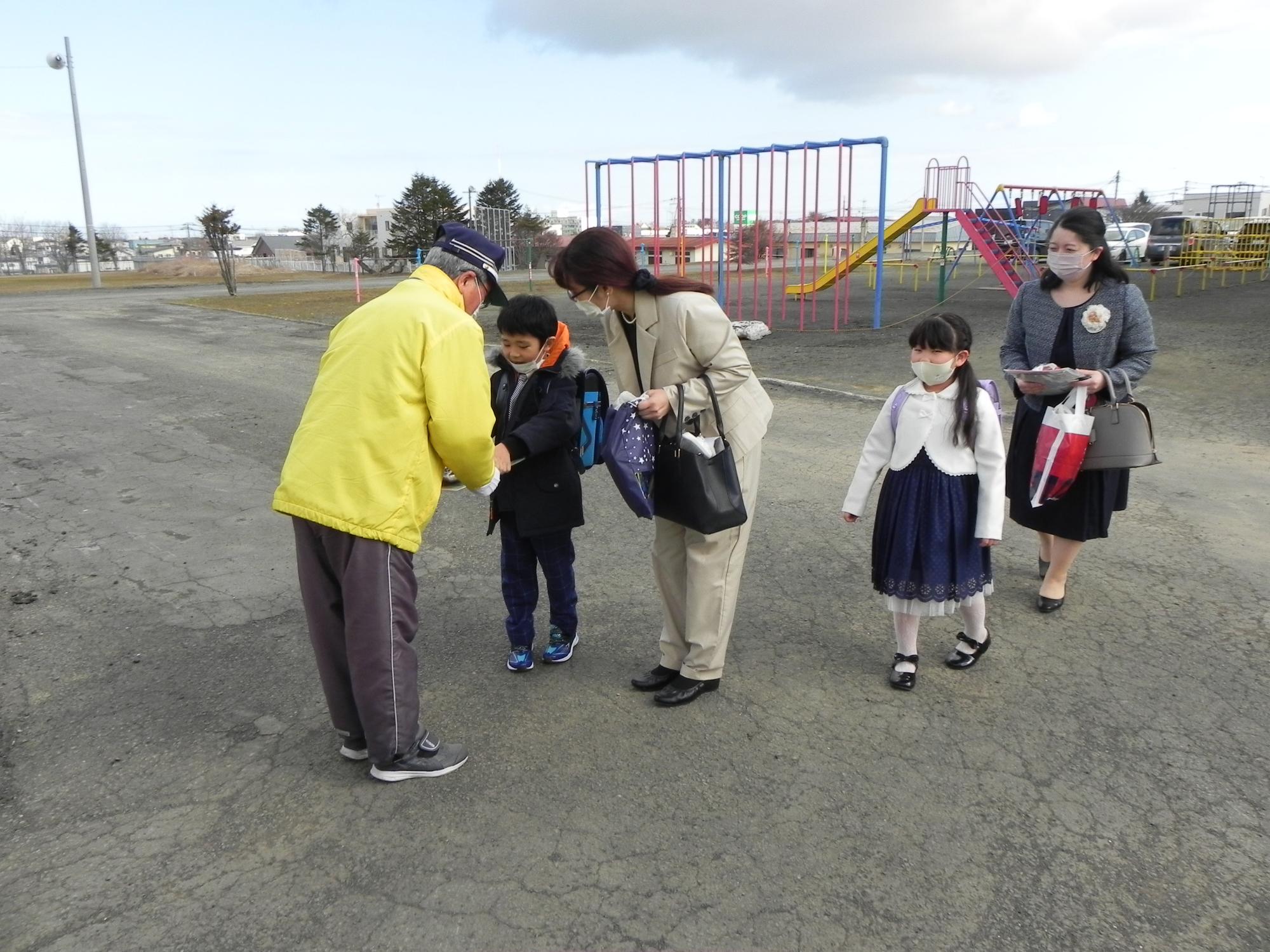 入学式で児童に啓発用品を渡す指導員